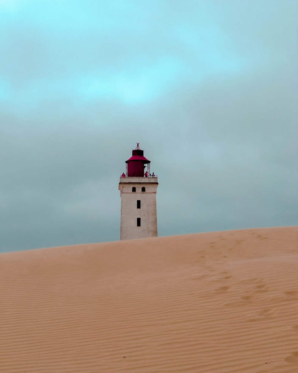 a light house sitting on top of a sandy hill