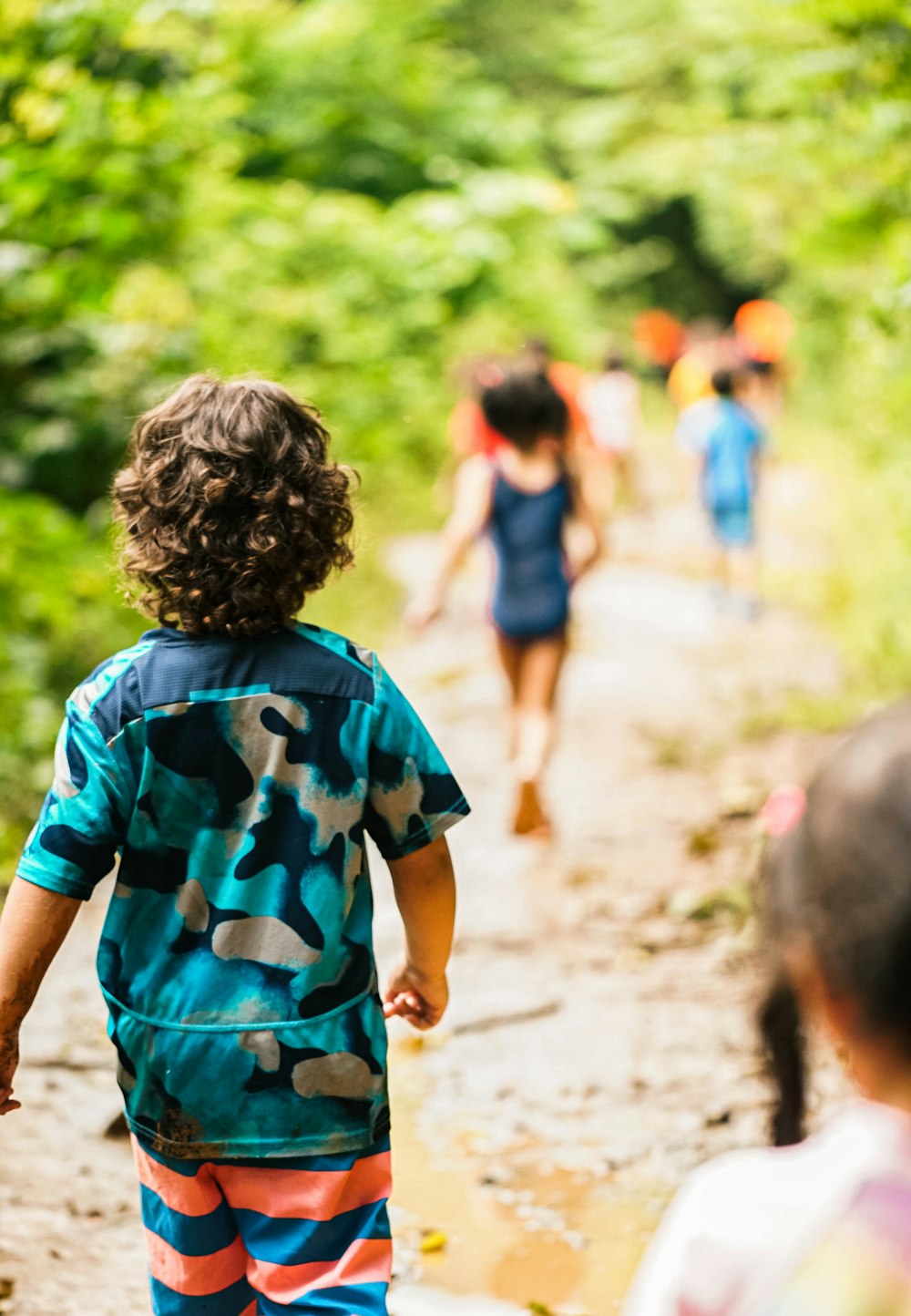 a group of children walking down a dirt road