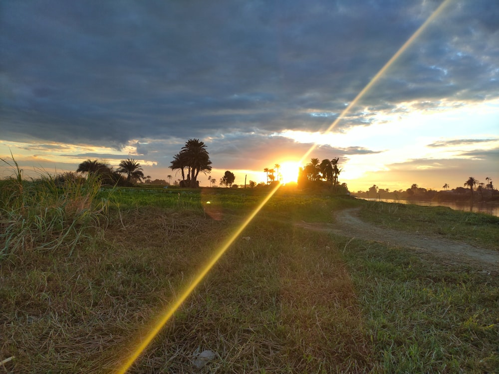 the sun is setting over a dirt road