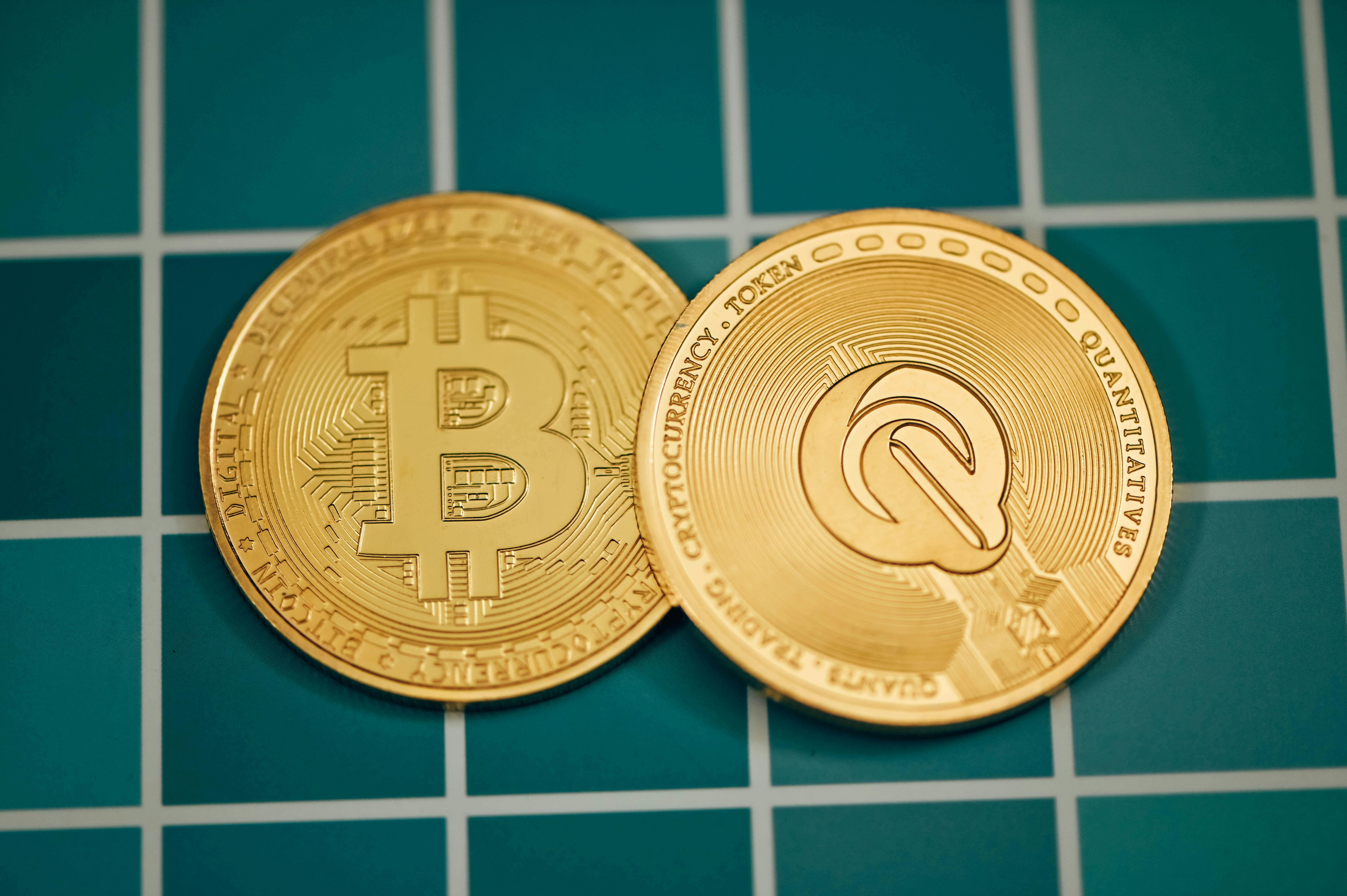 two gold bitcoins sitting on a blue tiled floor