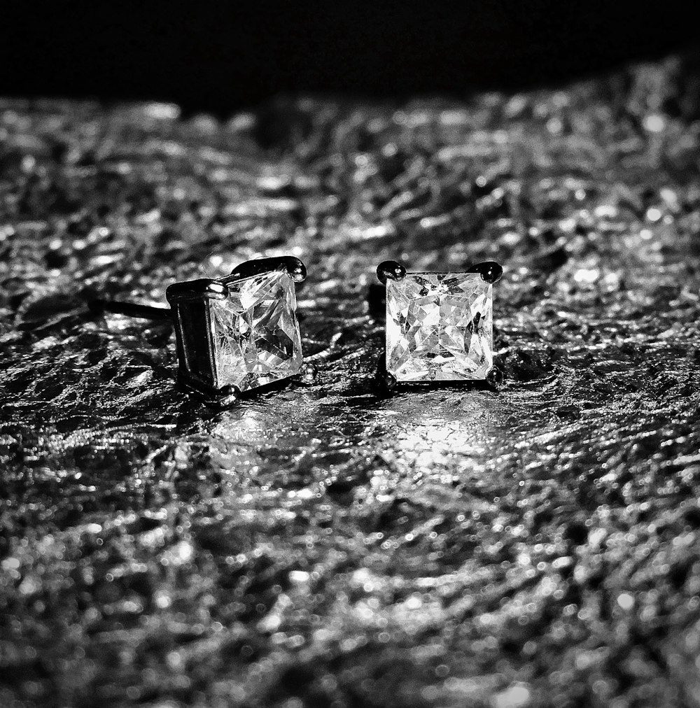 Photographie en noir et blanc de deux boucles d’oreilles carrées en diamant