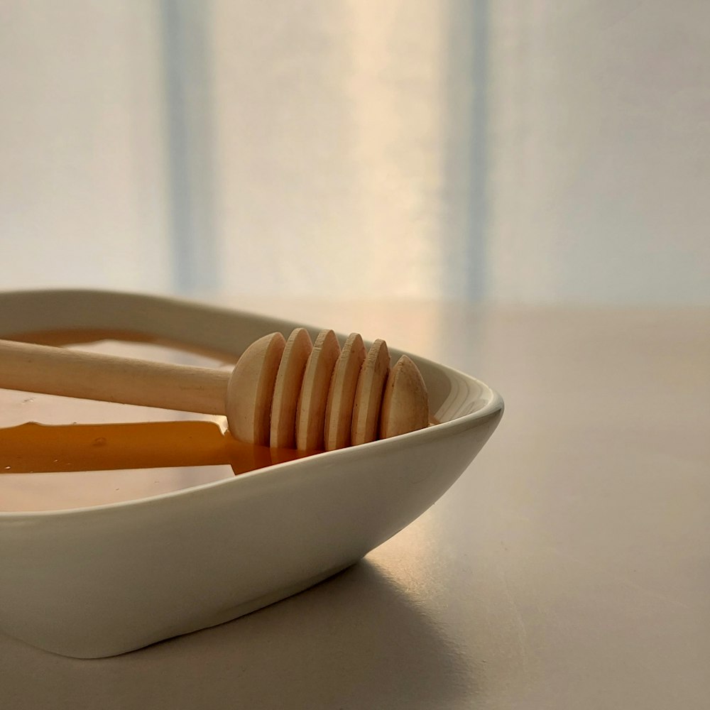 a white bowl filled with liquid and a wooden spoon