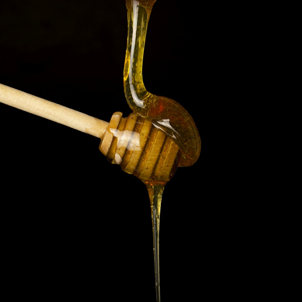 a honey dip being poured onto a wooden spoon