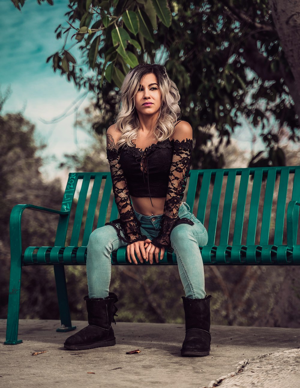 a woman is sitting on a green bench