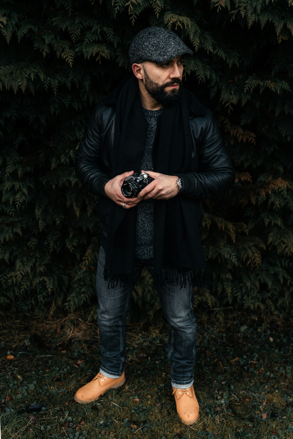 a man standing in front of a bush holding a camera