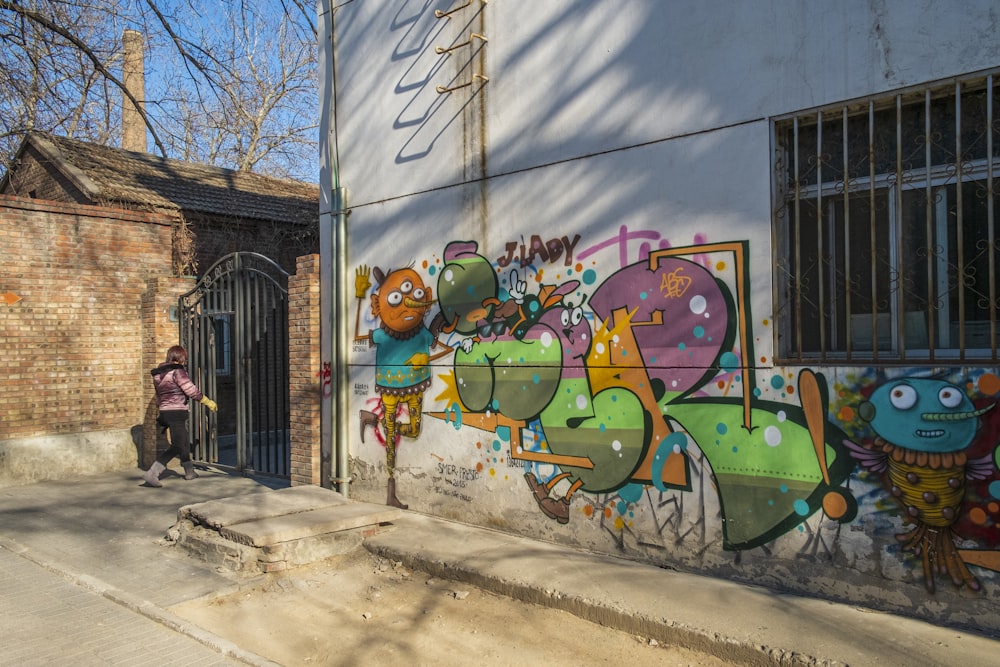 une personne debout devant un bâtiment avec des graffitis dessus