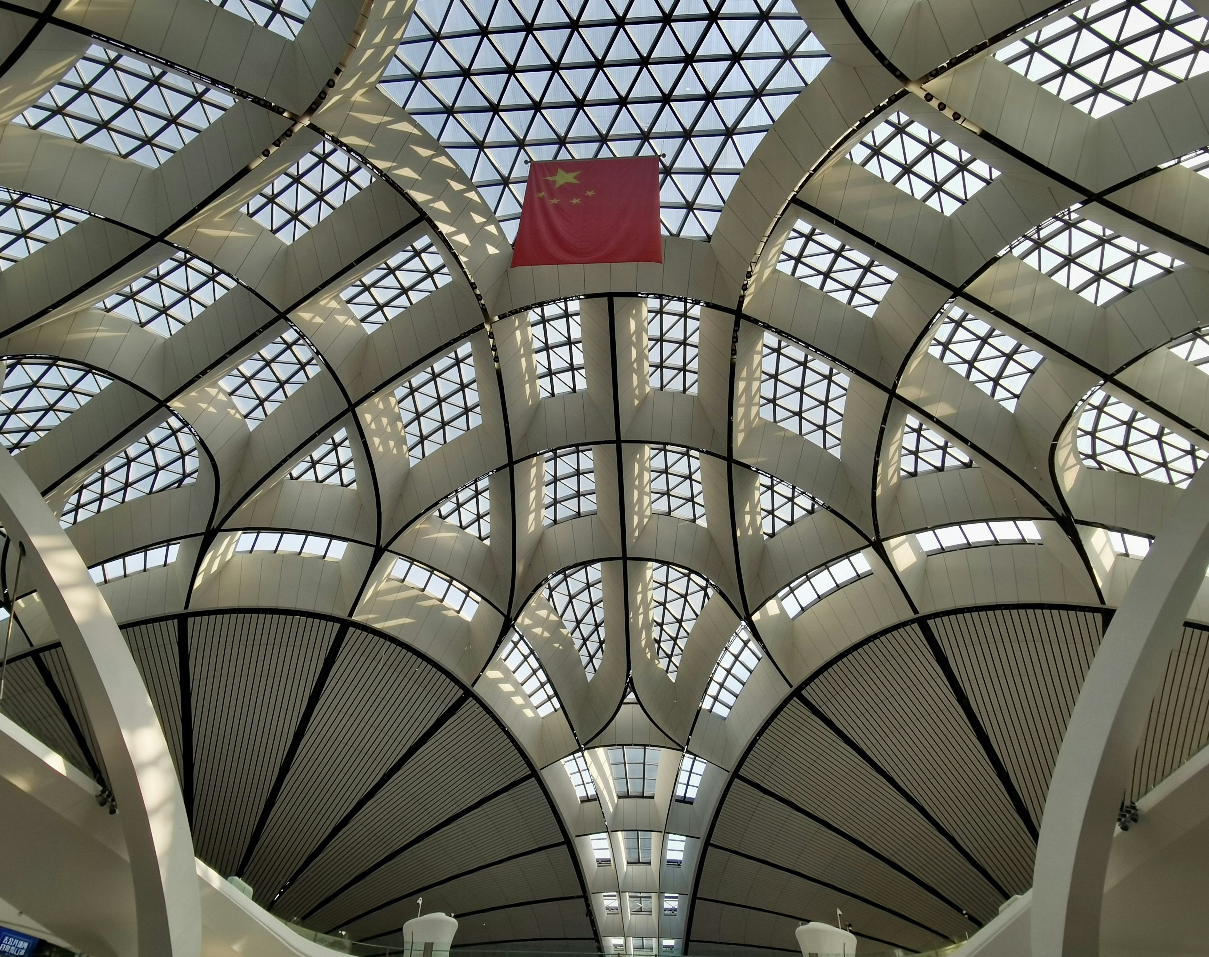 the ceiling of a large building with a red flag hanging from it's side