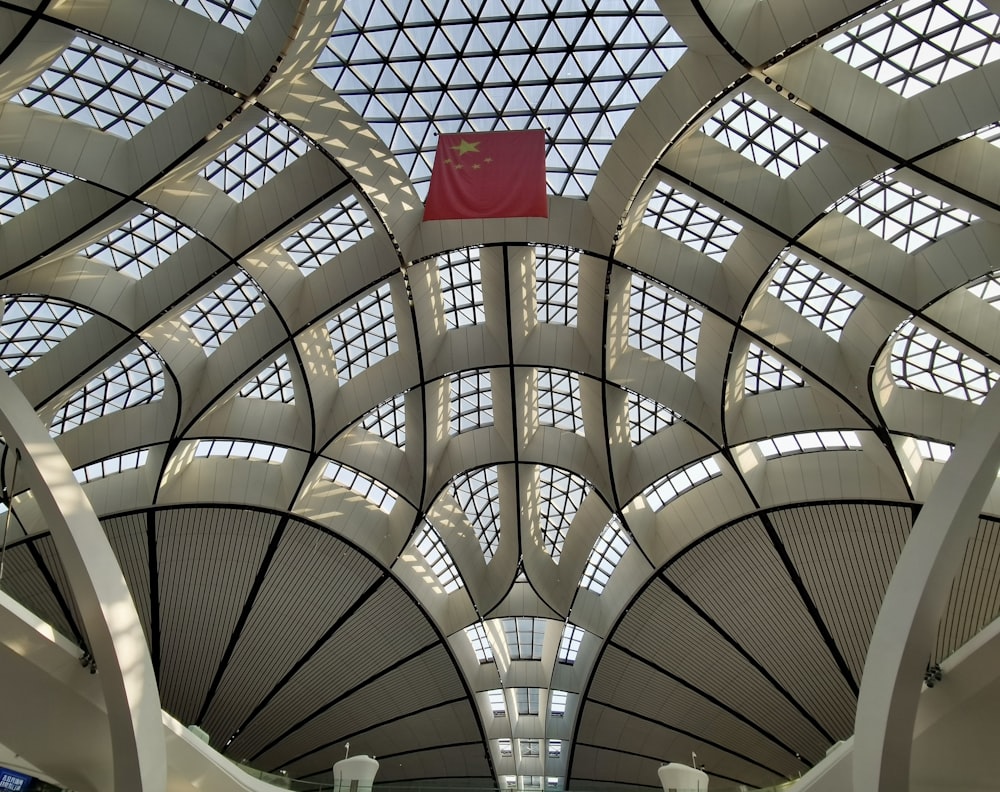the ceiling of a large building with a red flag hanging from it's side