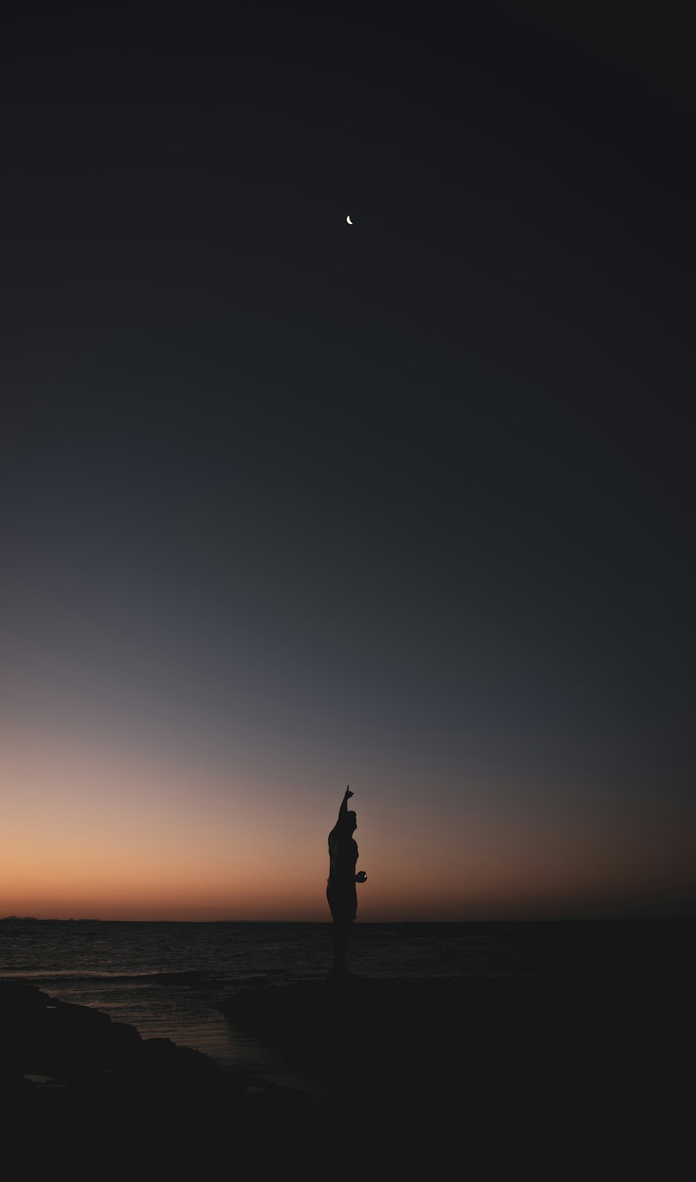 Una siluetta di una persona in piedi su una spiaggia al tramonto