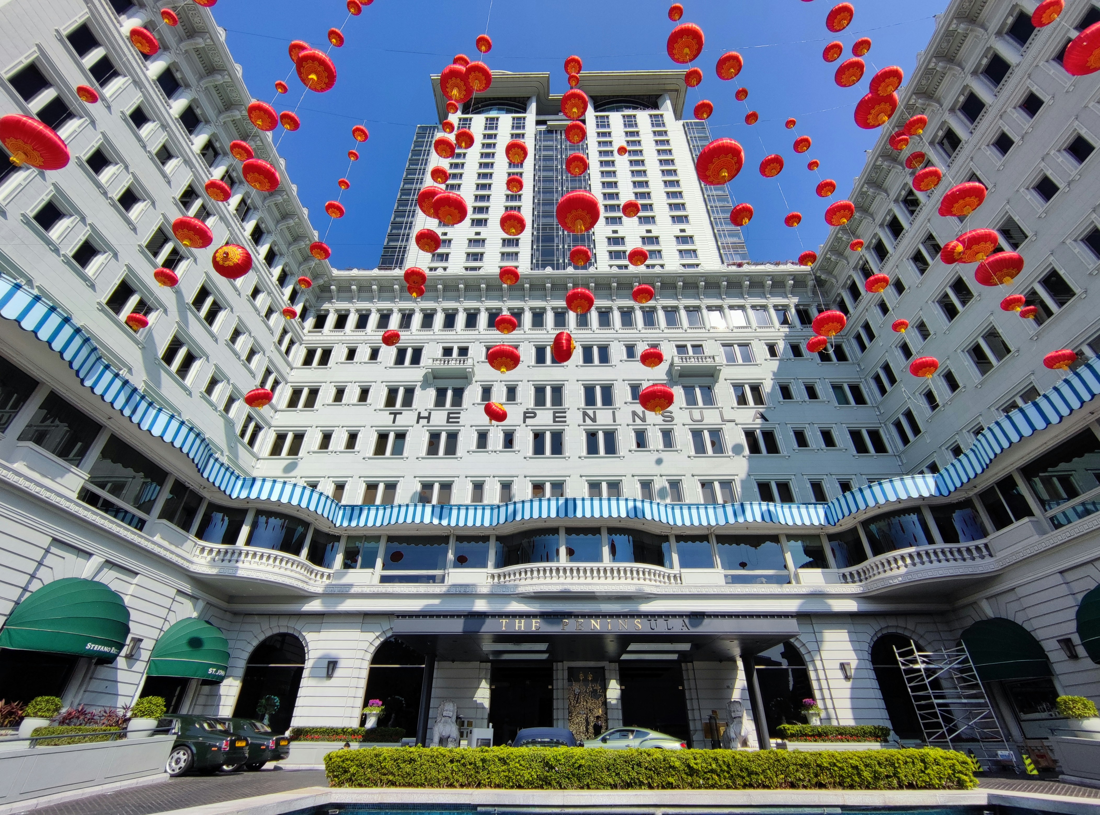 Red lanterns 'floating' in the air outside the Peninsula Hotel on Salisbury Road in Tsim Sha Tsui, Kowloon Peninsula. Red lanterns are hung for celebration or festival activities as a common practice in traditional Chinese culture. The lanterns are hung up by wires. The Peninsula Hotel, opened in 1928 before the Second World War and expanded in 1994, has a Baroque architectural design （巴洛克建築風格）. It is a touristic place and landmark in Tsim Sha Tsui and id one of the most luxurious and iconic hotel in Hong Kong.