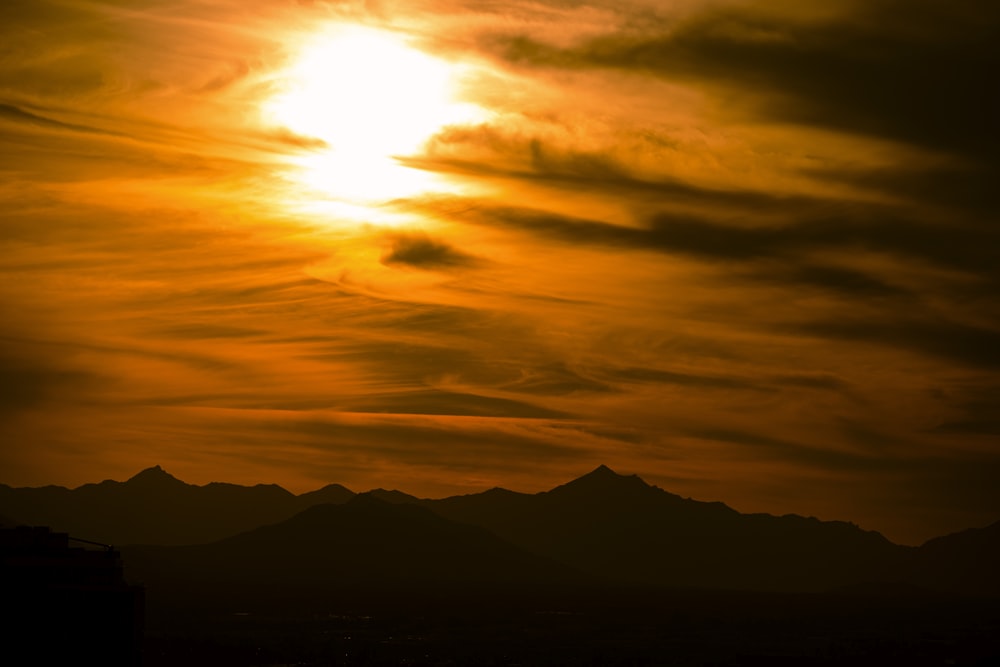 the sun is setting over a mountain range