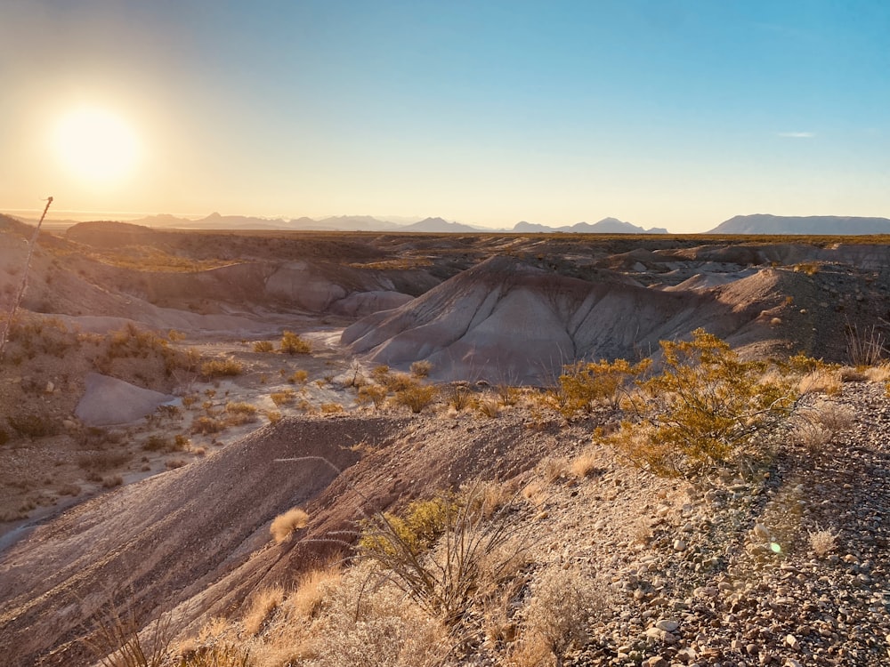 the sun is setting over a desert landscape