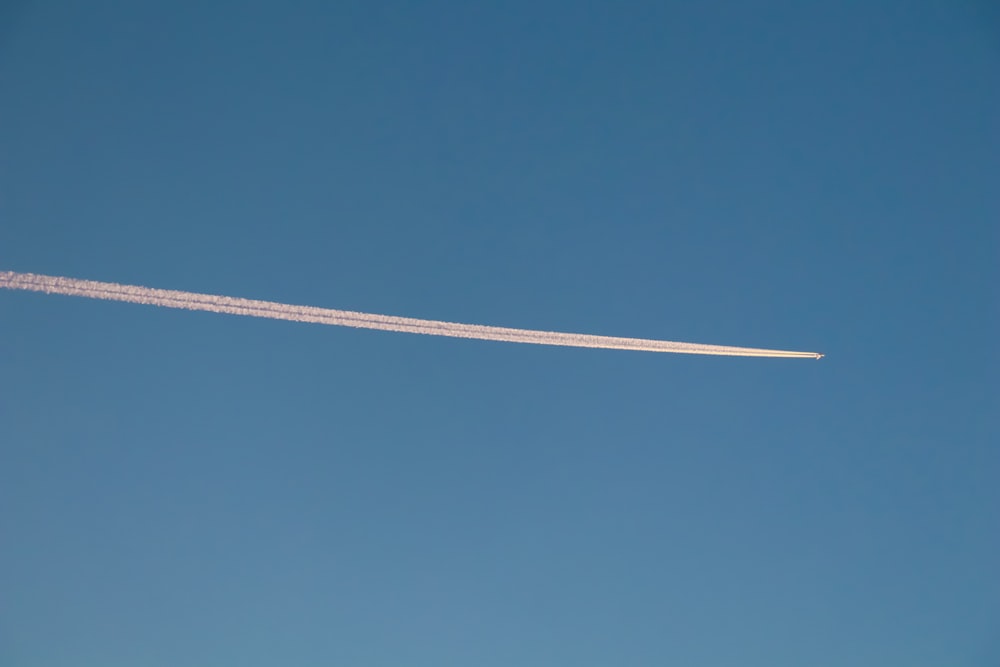 a contrail flying through a blue sky