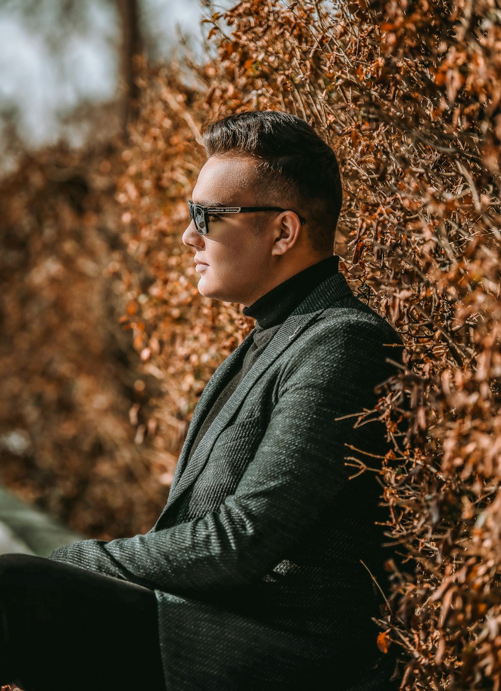 a man in a suit and sunglasses sitting against a wall