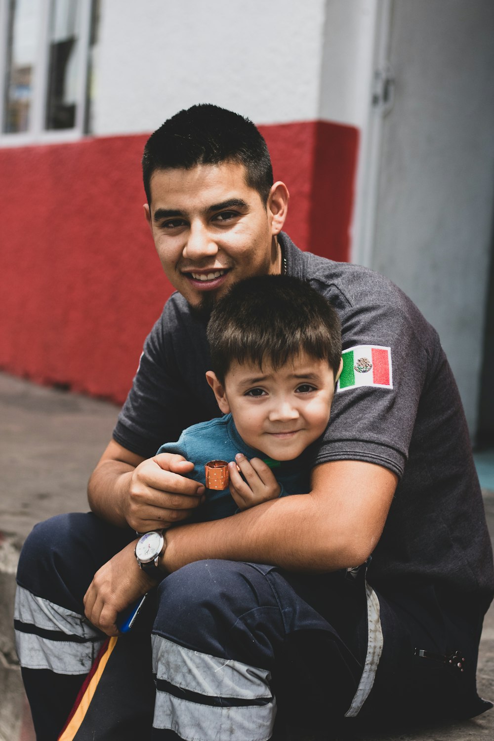 a man sitting on the ground holding a small boy