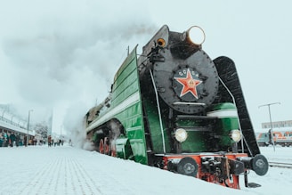 a green and black train traveling down train tracks