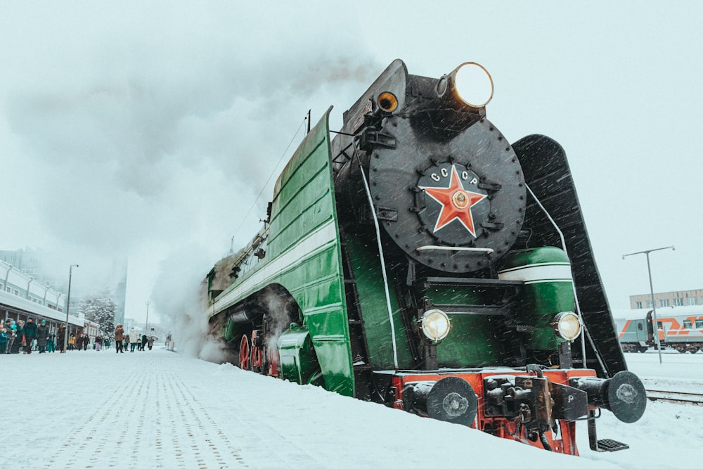 Ein grün-schwarzer Zug, der die Bahngleise hinunterfährt