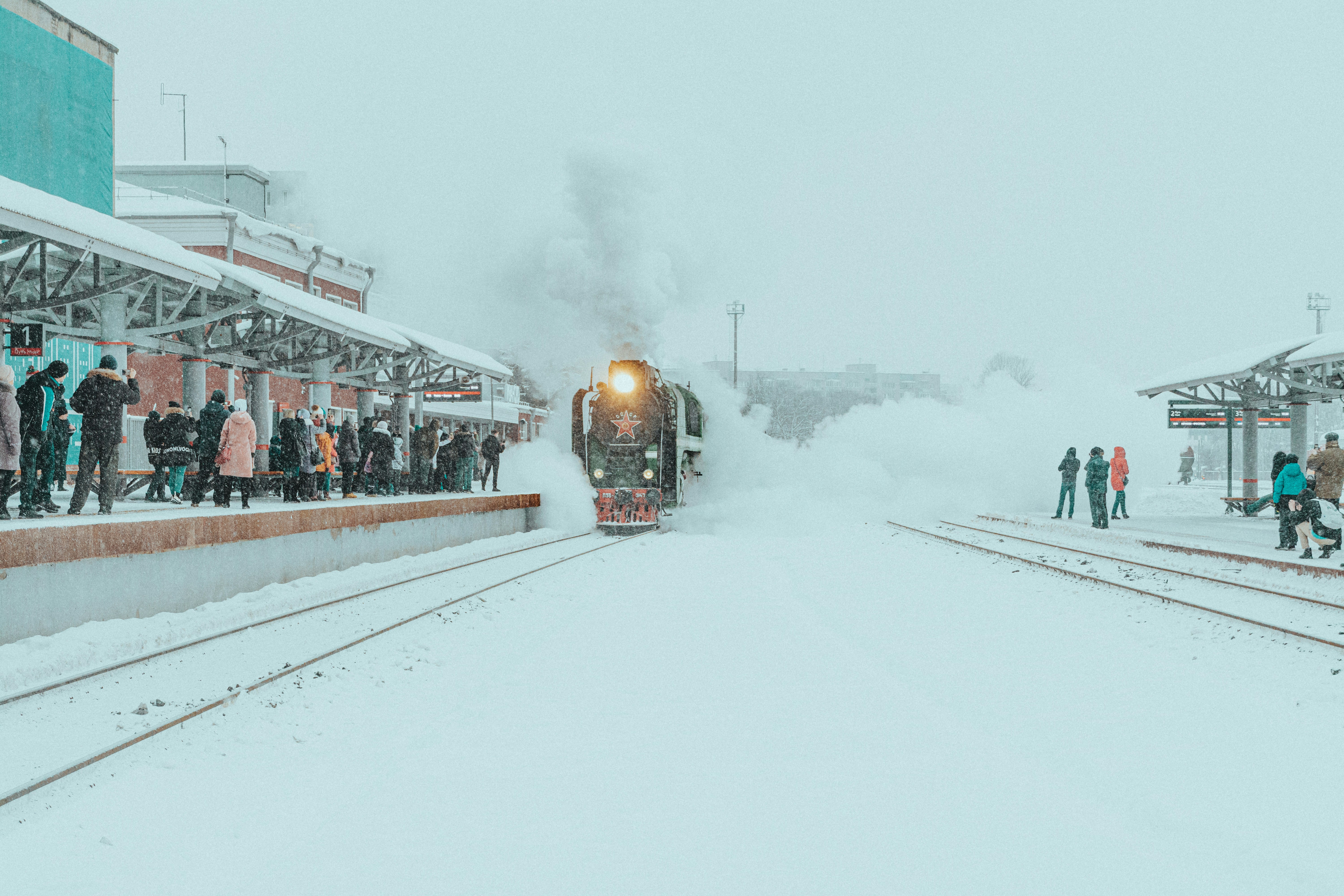 a train traveling down train tracks next to a snow covered platform, soviet locomotive P36-0147, 1955