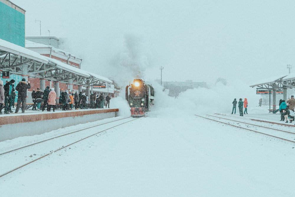a train traveling down train tracks next to a snow covered platform