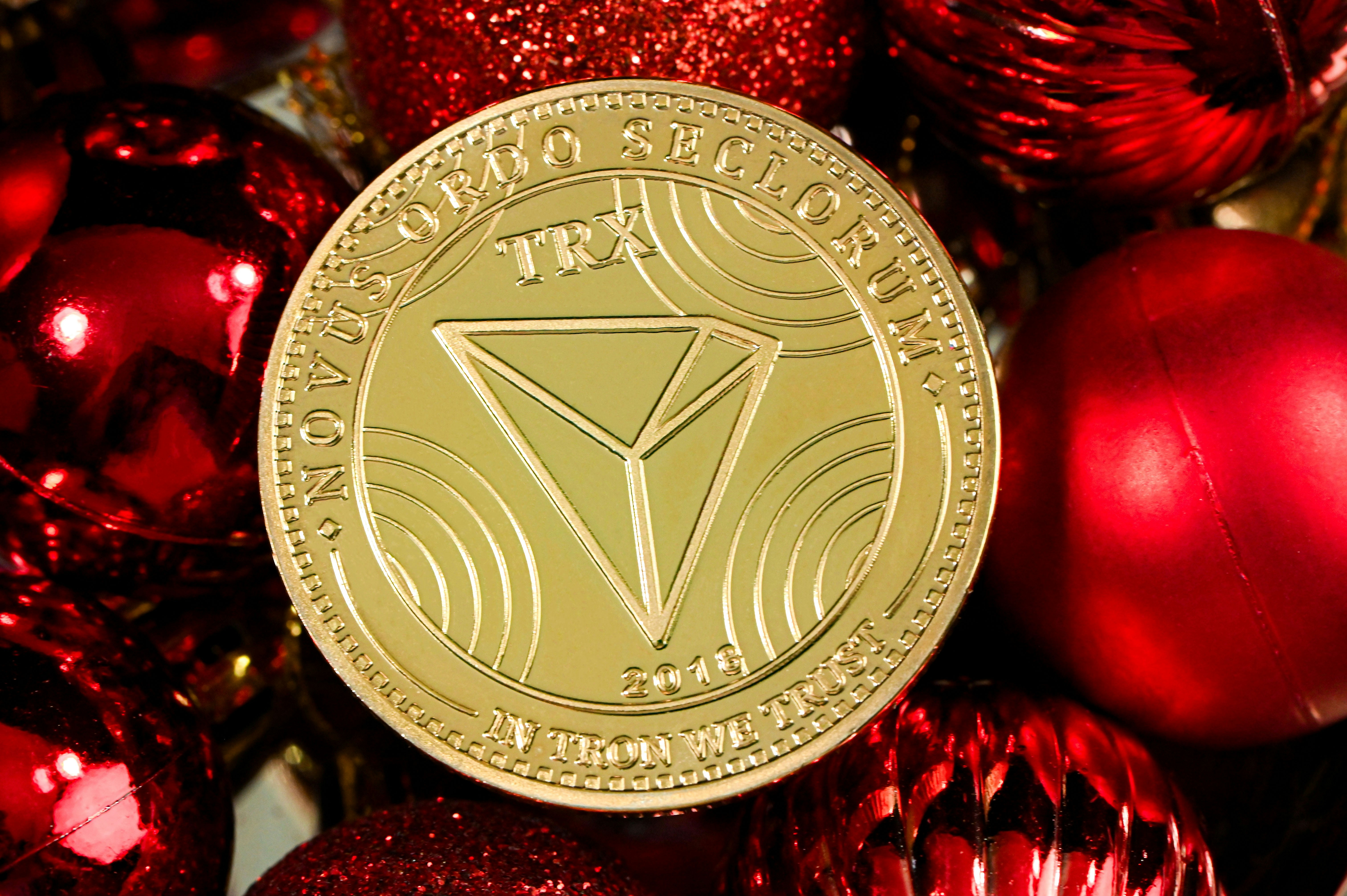 a gold coin sitting on top of a pile of red ornaments, TRON on red Christmas ornaments.