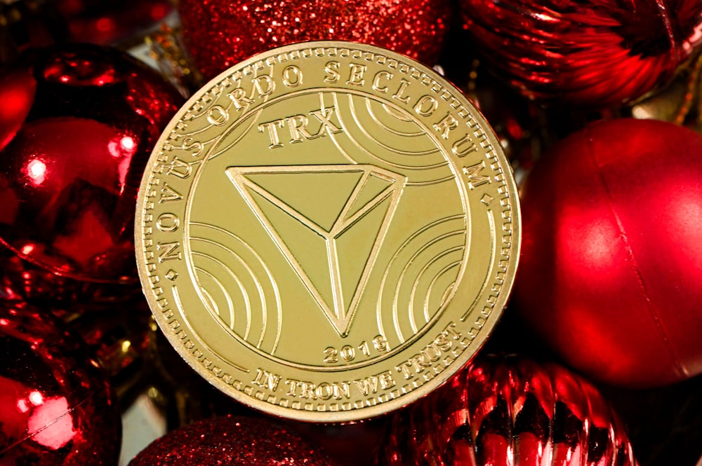 a gold coin sitting on top of a pile of red ornaments