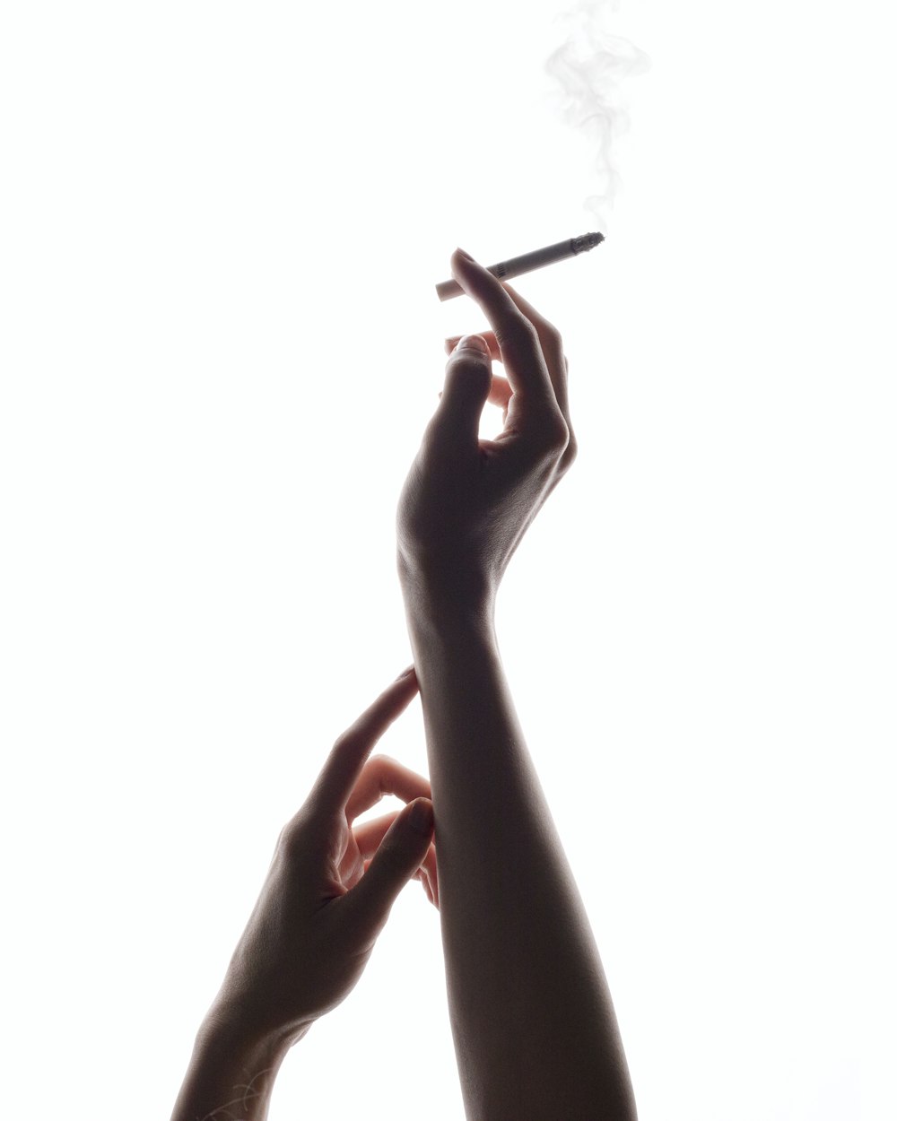 two hands holding a cigarette in front of a white background
