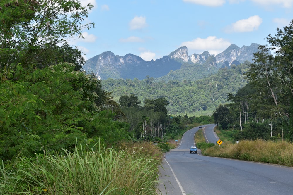 Un coche conduciendo por una carretera con montañas en el fondo