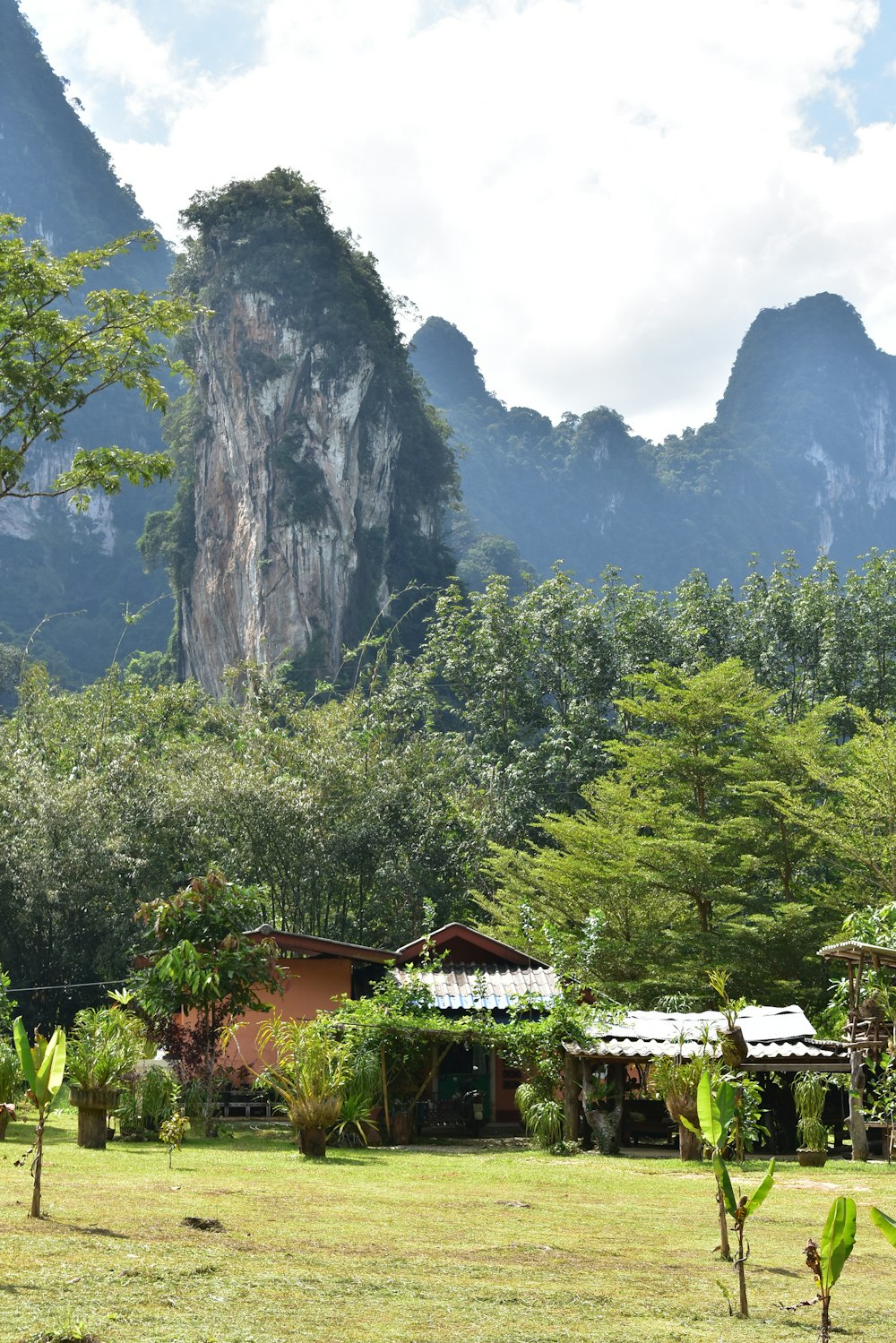 Une maison au milieu d’un champ avec des montagnes en arrière-plan