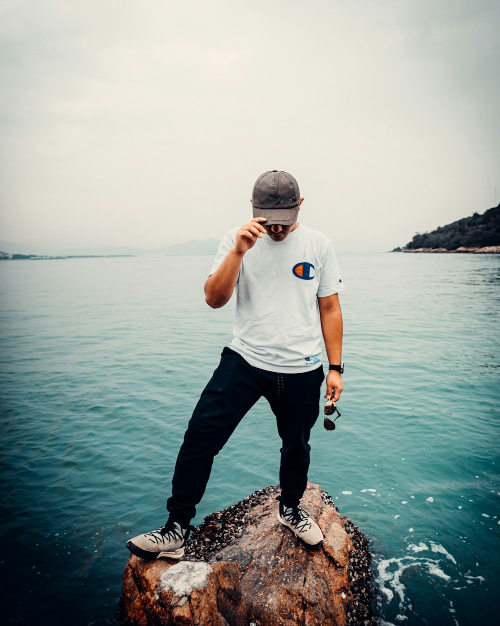 a man standing on top of a rock near the ocean