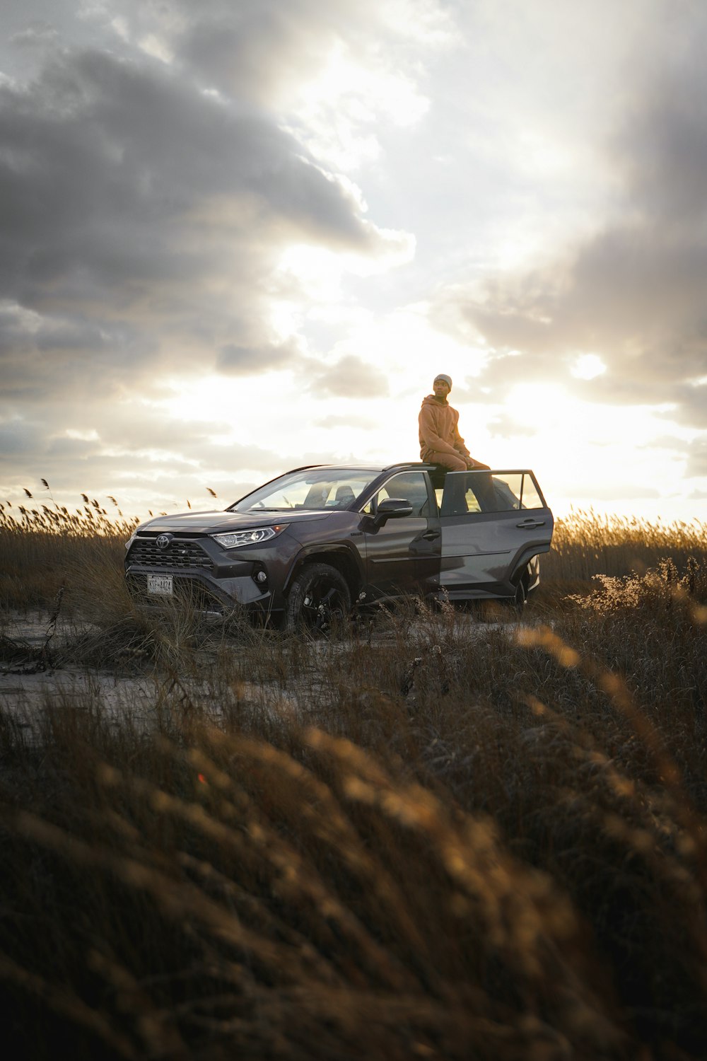 a man standing on top of a car in a field