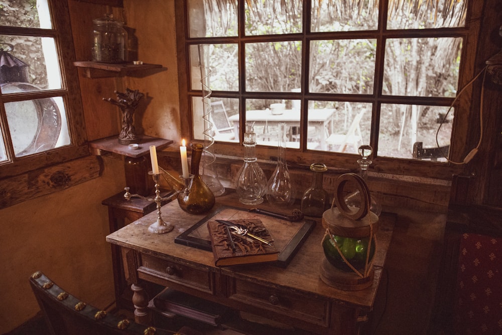 a wooden table topped with a bottle of wine next to a window