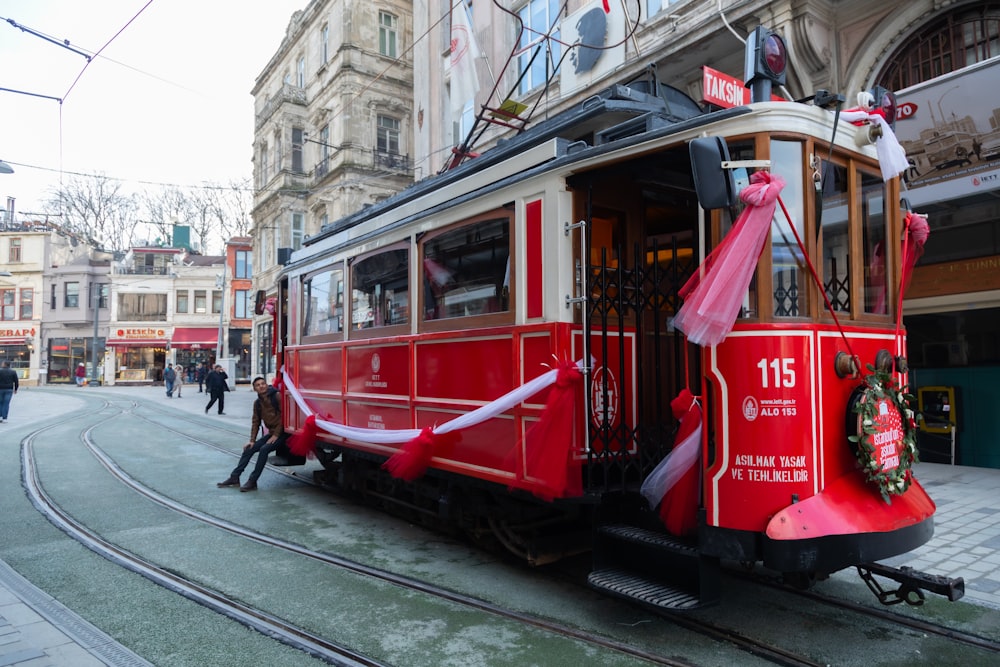 a red trolley car with a christmas wreath on the front