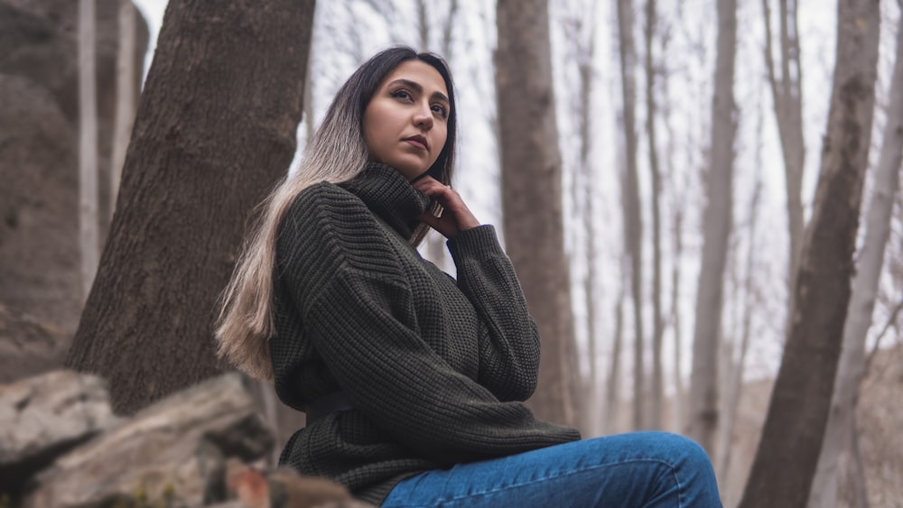 Una donna seduta su una roccia nel bosco