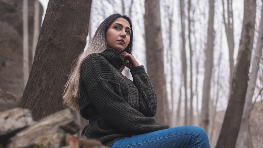 a woman sitting on a rock in the woods