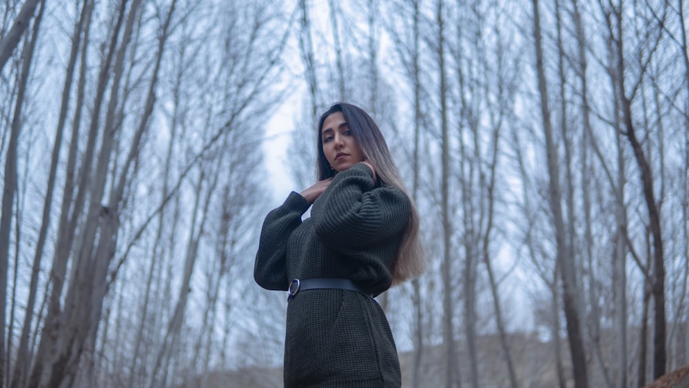 a woman standing in a forest with trees in the background