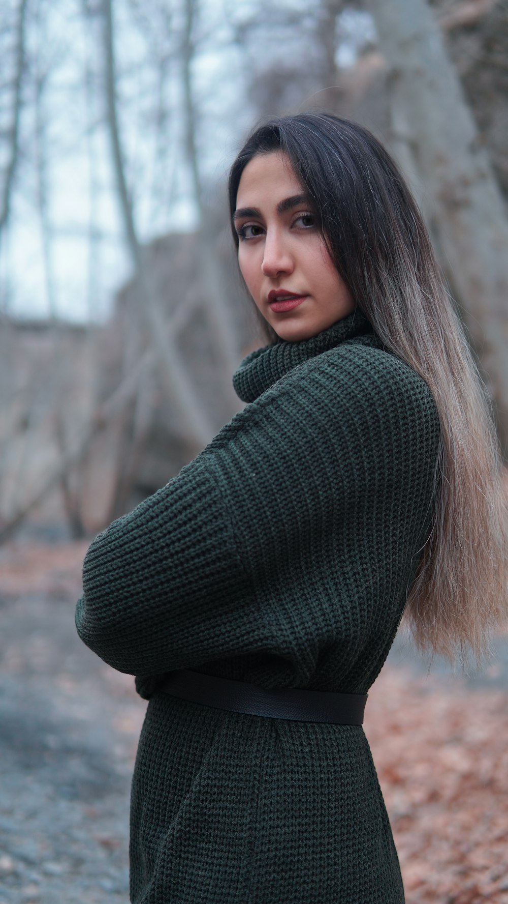 a woman with long hair standing in the woods