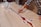 A person is working on a wooden table with artistic inlays, using a tool to shape or fill a resin river design. The surface is predominantly light-colored wood, and there are various white outlines possibly marking where resin will be placed.