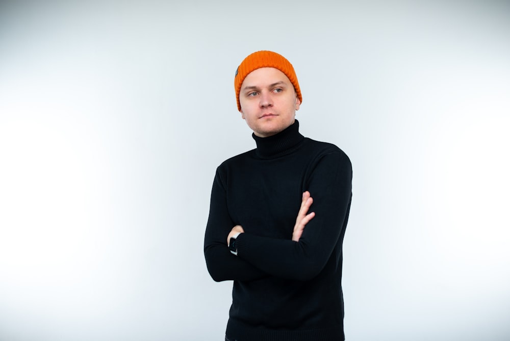 Un uomo con un maglione nero e un cappello arancione