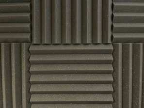Various panels with a grooved pattern arranged in a symmetrical manner. The panels have a textured surface and appear to be made of foam material, commonly used for soundproofing.