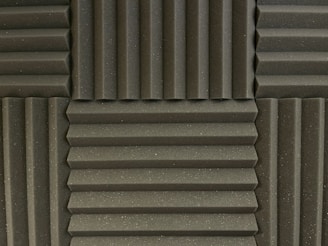 Various panels with a grooved pattern arranged in a symmetrical manner. The panels have a textured surface and appear to be made of foam material, commonly used for soundproofing.
