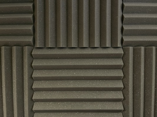 Various panels with a grooved pattern arranged in a symmetrical manner. The panels have a textured surface and appear to be made of foam material, commonly used for soundproofing.