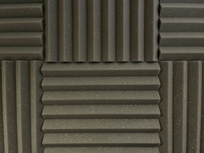 Various panels with a grooved pattern arranged in a symmetrical manner. The panels have a textured surface and appear to be made of foam material, commonly used for soundproofing.