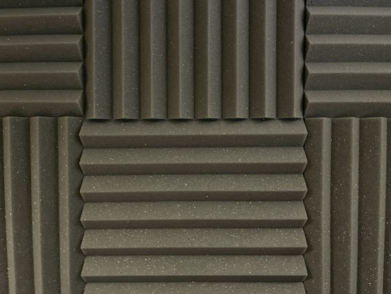 Various panels with a grooved pattern arranged in a symmetrical manner. The panels have a textured surface and appear to be made of foam material, commonly used for soundproofing.