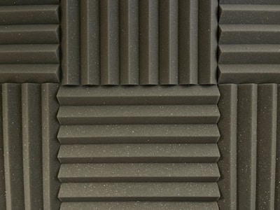 Various panels with a grooved pattern arranged in a symmetrical manner. The panels have a textured surface and appear to be made of foam material, commonly used for soundproofing.