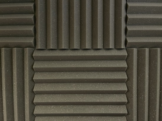 Various panels with a grooved pattern arranged in a symmetrical manner. The panels have a textured surface and appear to be made of foam material, commonly used for soundproofing.