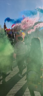 A group of friends laughing and enjoying a photo session with colorful smoke clouds in the background.