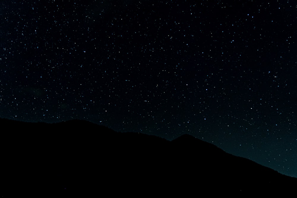o céu noturno está cheio de estrelas acima de uma montanha