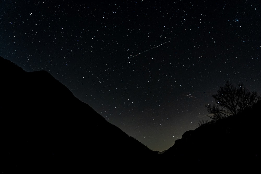 the night sky with stars above a mountain