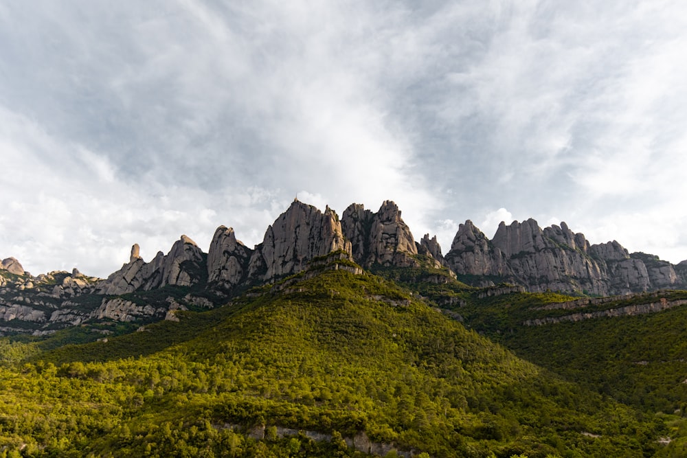 the mountains are covered in green vegetation under a cloudy sky