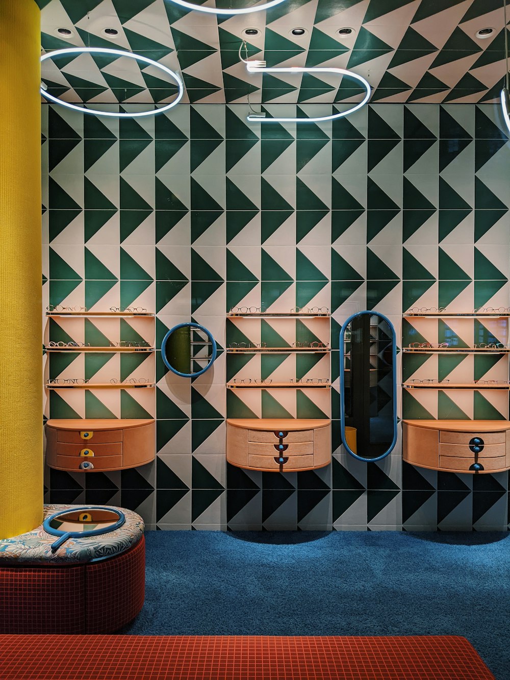 a bathroom with a colorful tiled wall and a round mirror